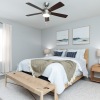 a bedroom with a bed, chair, nightstand and a wooden bench